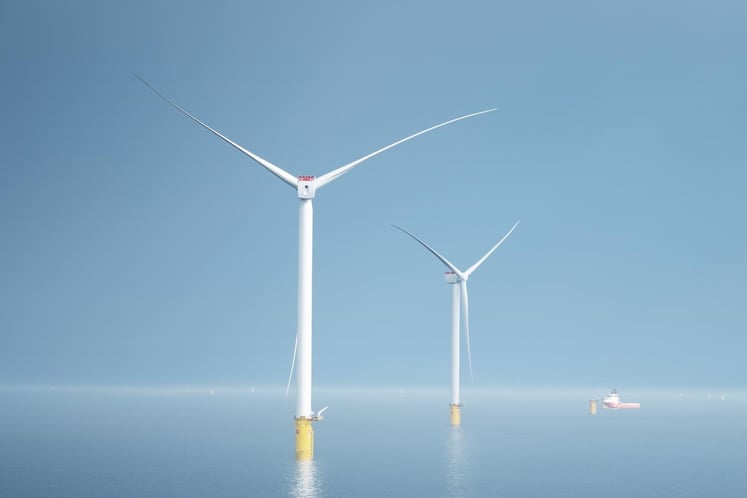 View of Hollandse Kust Zuid offshore wind park with two wind mills in the center of the sea, that has the same light blue color as the sky above.